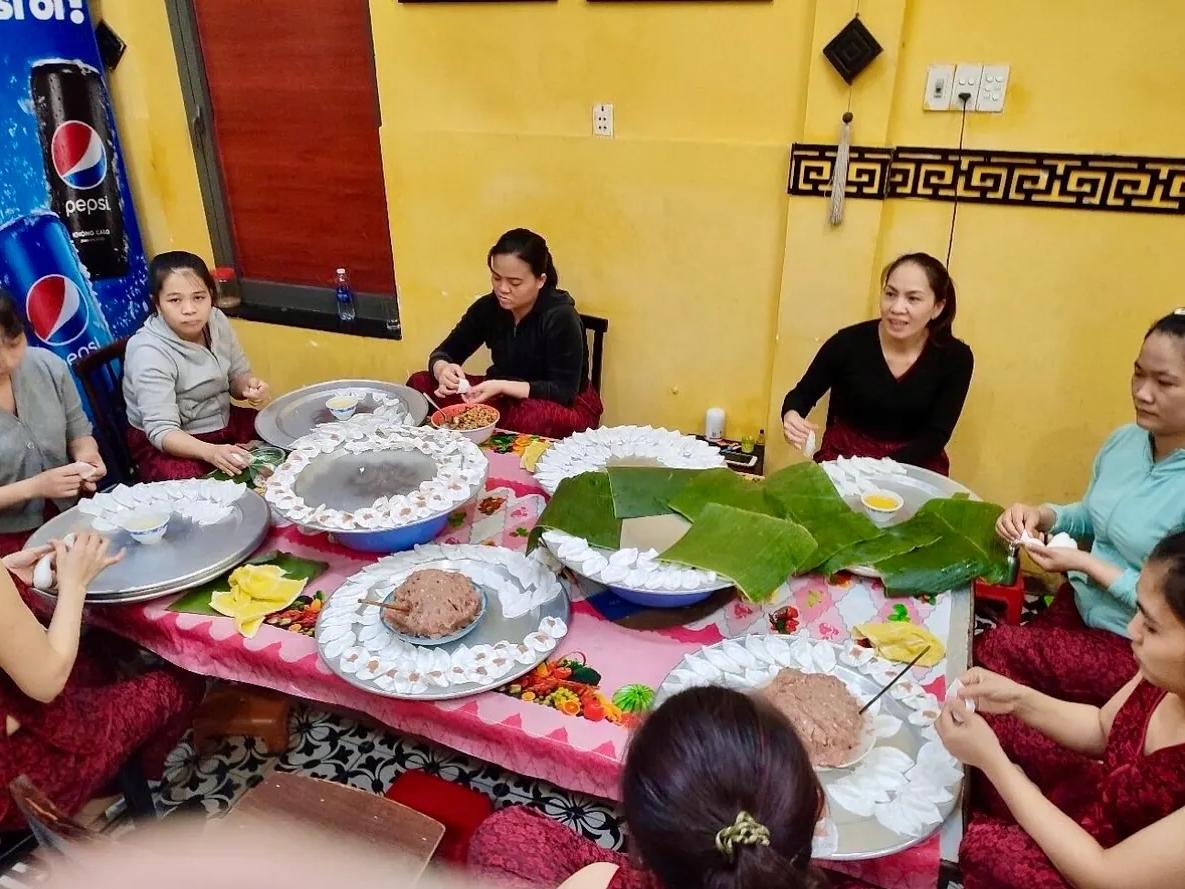 Local cooks folding white rose dumplings around a shared table in a Hoi An family kitchen