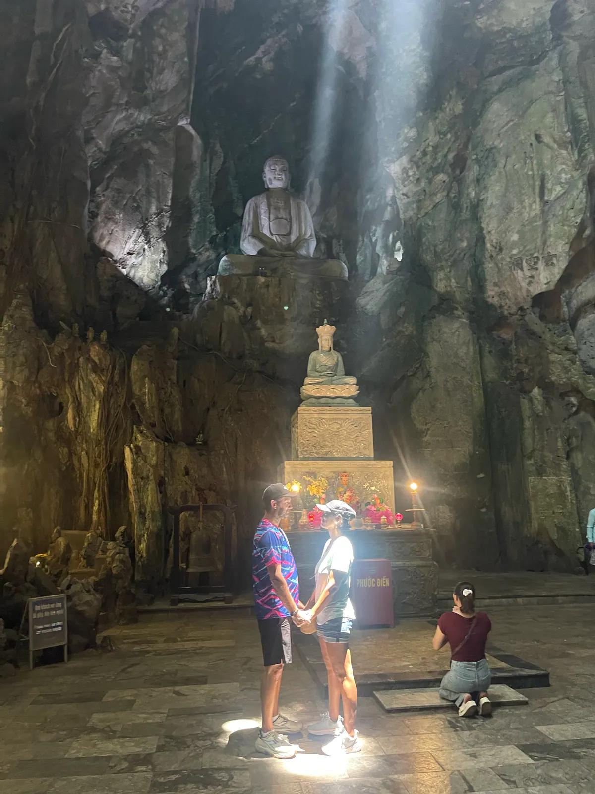 Guests standing in the shaft of light inside a Marble Mountains cave
