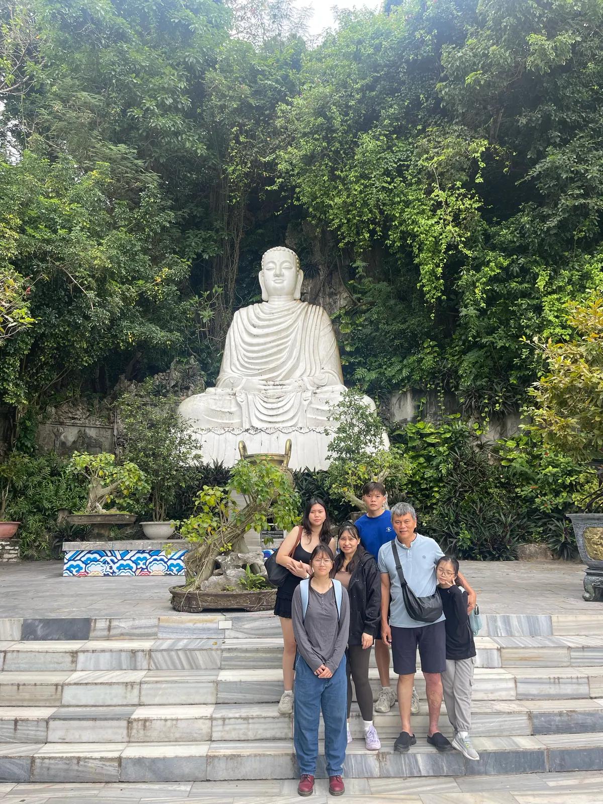 A family standing below the Lady Buddha figure at Linh Ung Pagoda on Son Tra