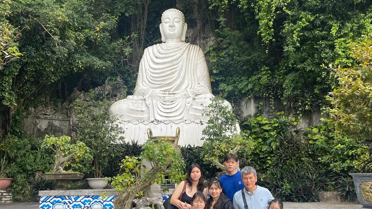 A family standing below the Lady Buddha figure at Linh Ung Pagoda on Son Tra