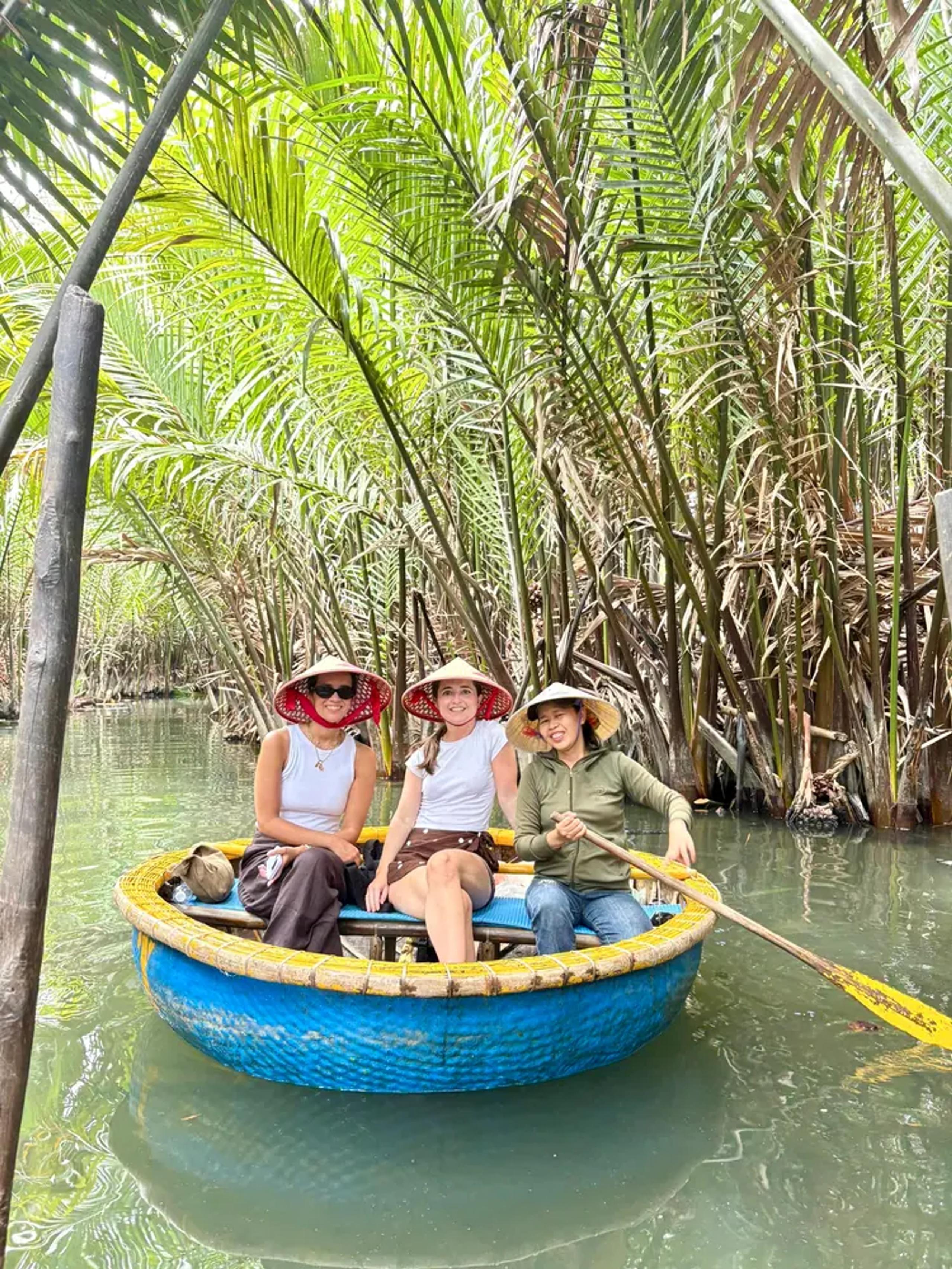 Guests in a round bamboo basket boat in the water coconut palms near Hoi An