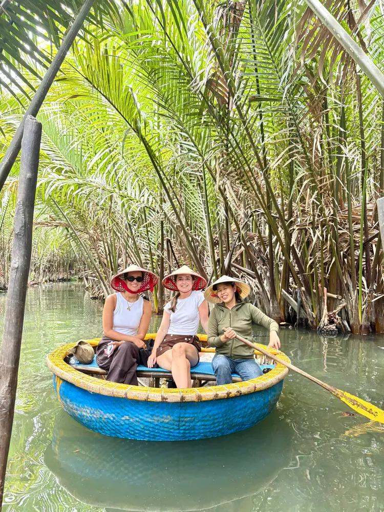 Guests in a round bamboo basket boat in the water coconut palms near Hoi An