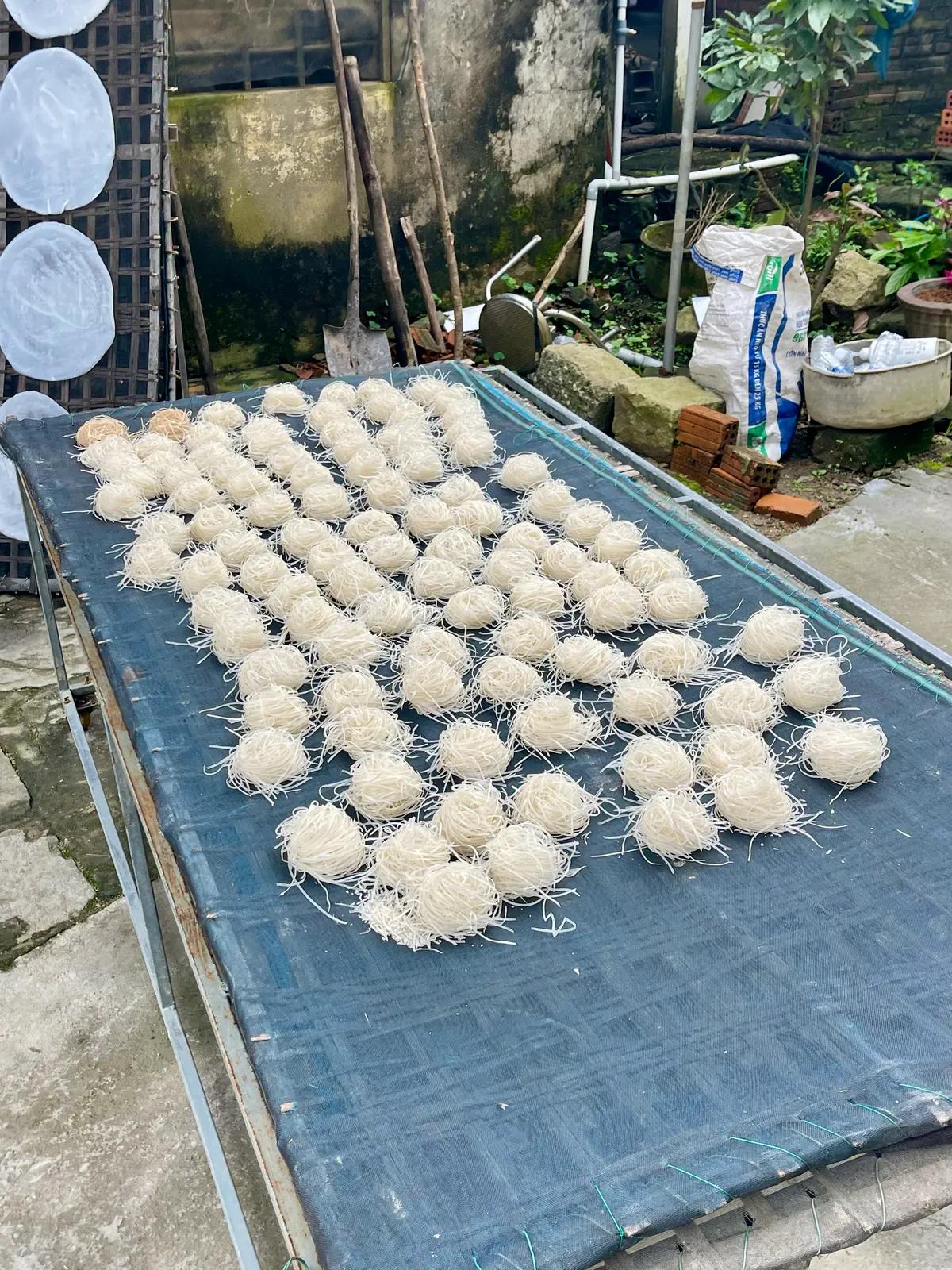 Hand-cut Mi Quang noodles laid out to dry outside the village kitchen
