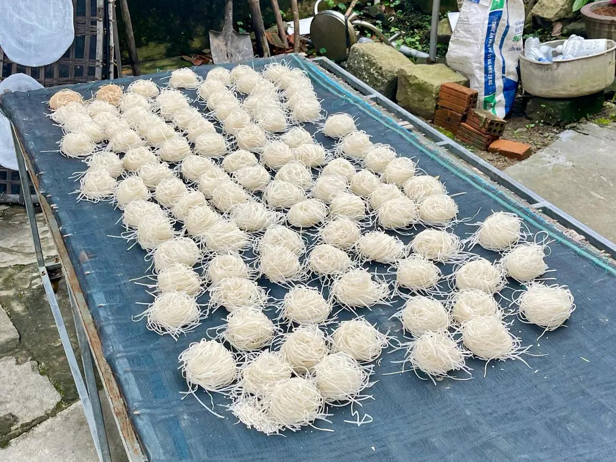 Hand-cut Mi Quang noodles laid out to dry outside the village kitchen