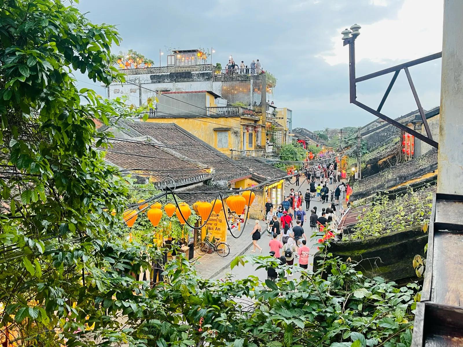 A Hoi An Ancient Town street seen from above, crowded with people between yellow buildings and tiled roofs