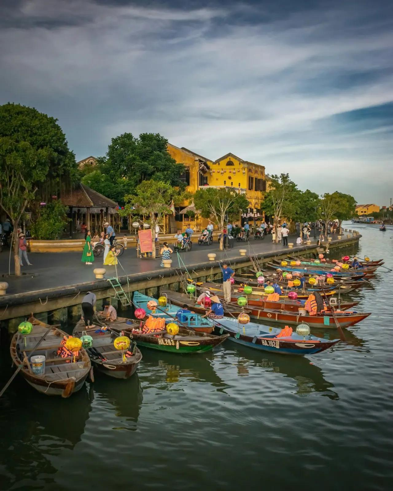 Hoi An Ancient Town at dusk, with the yellow riverfront houses and boats moored on the Thu Bon