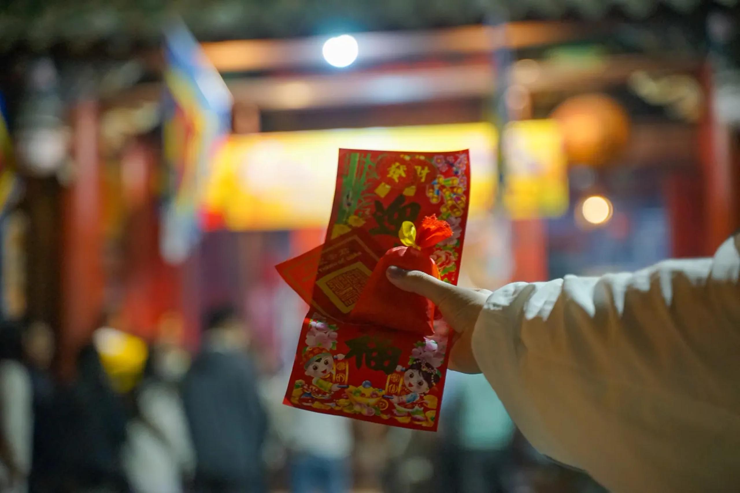 The three items taken home from the temple — a small red pouch of rice, a paper charm and a red fortune envelope