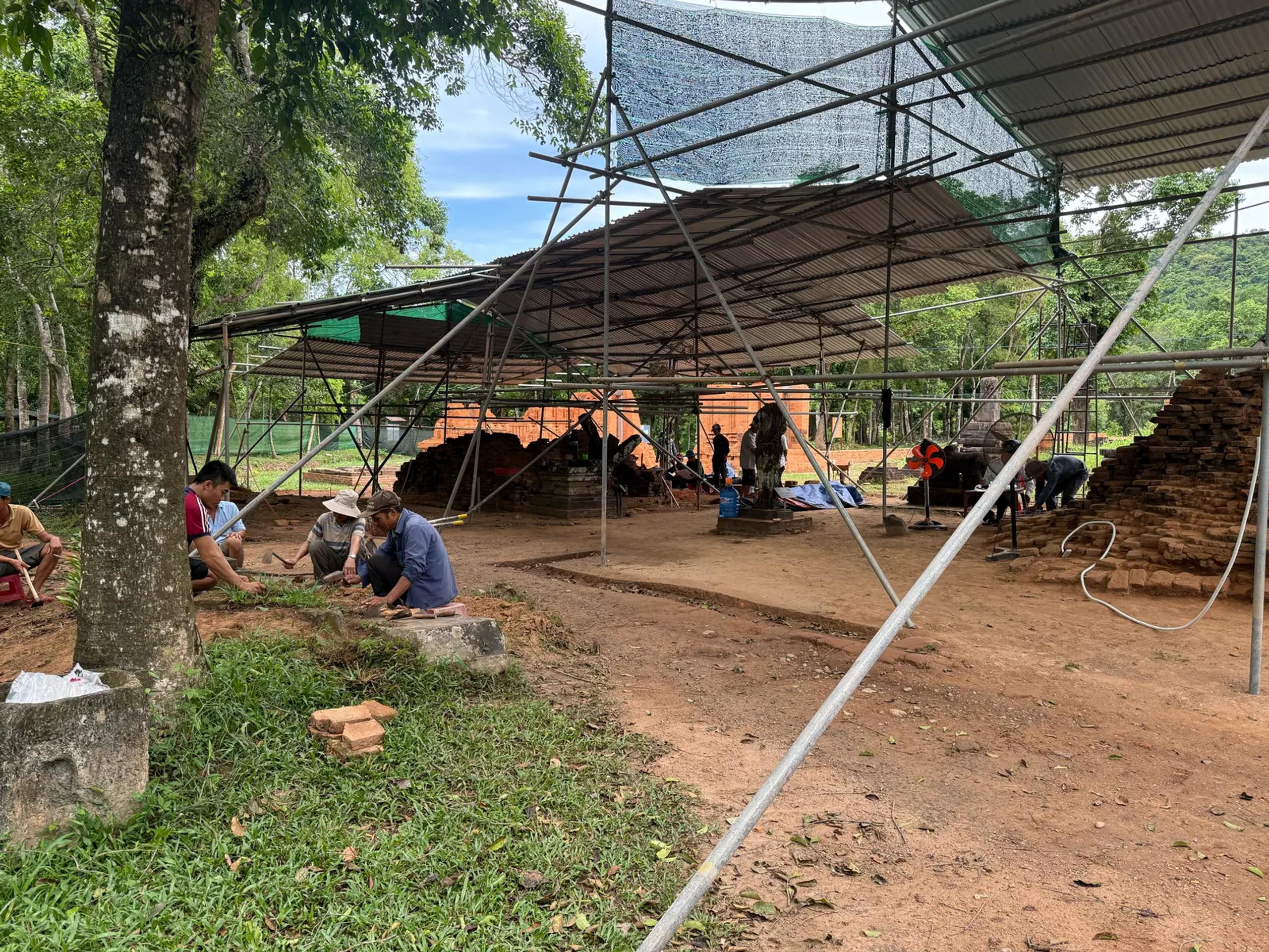 Archaeologists at work restoring a temple group under a shelter at My Son