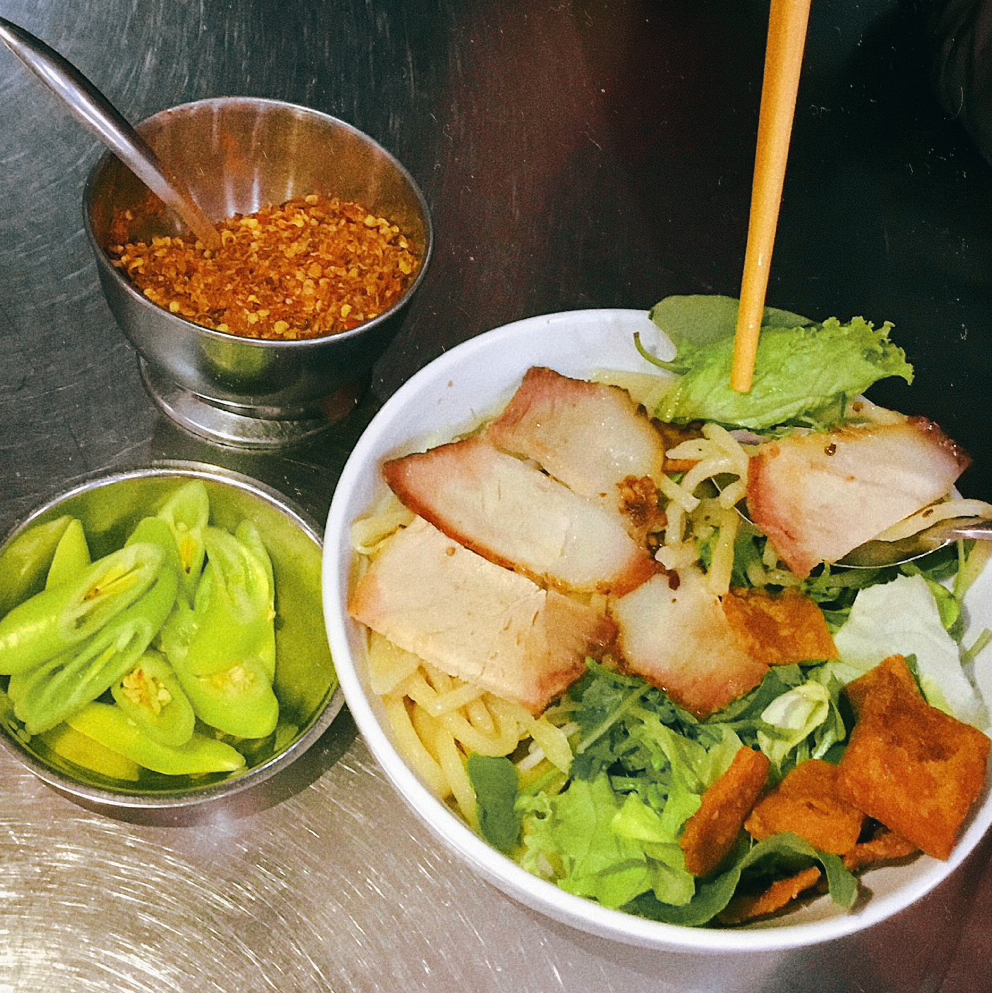A bowl of cao lầu with sliced pork, greens and crispy crackers, fresh chili on the side, at Quán Cao Lầu Thanh