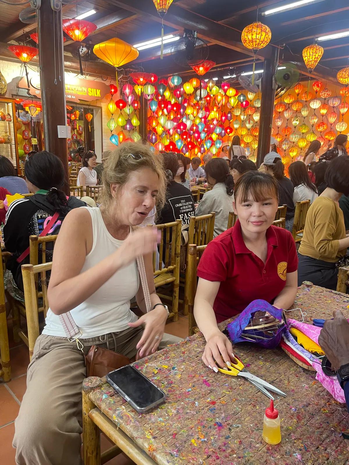 A guest making a silk lantern with a craftswoman in a Hoi An lantern workshop