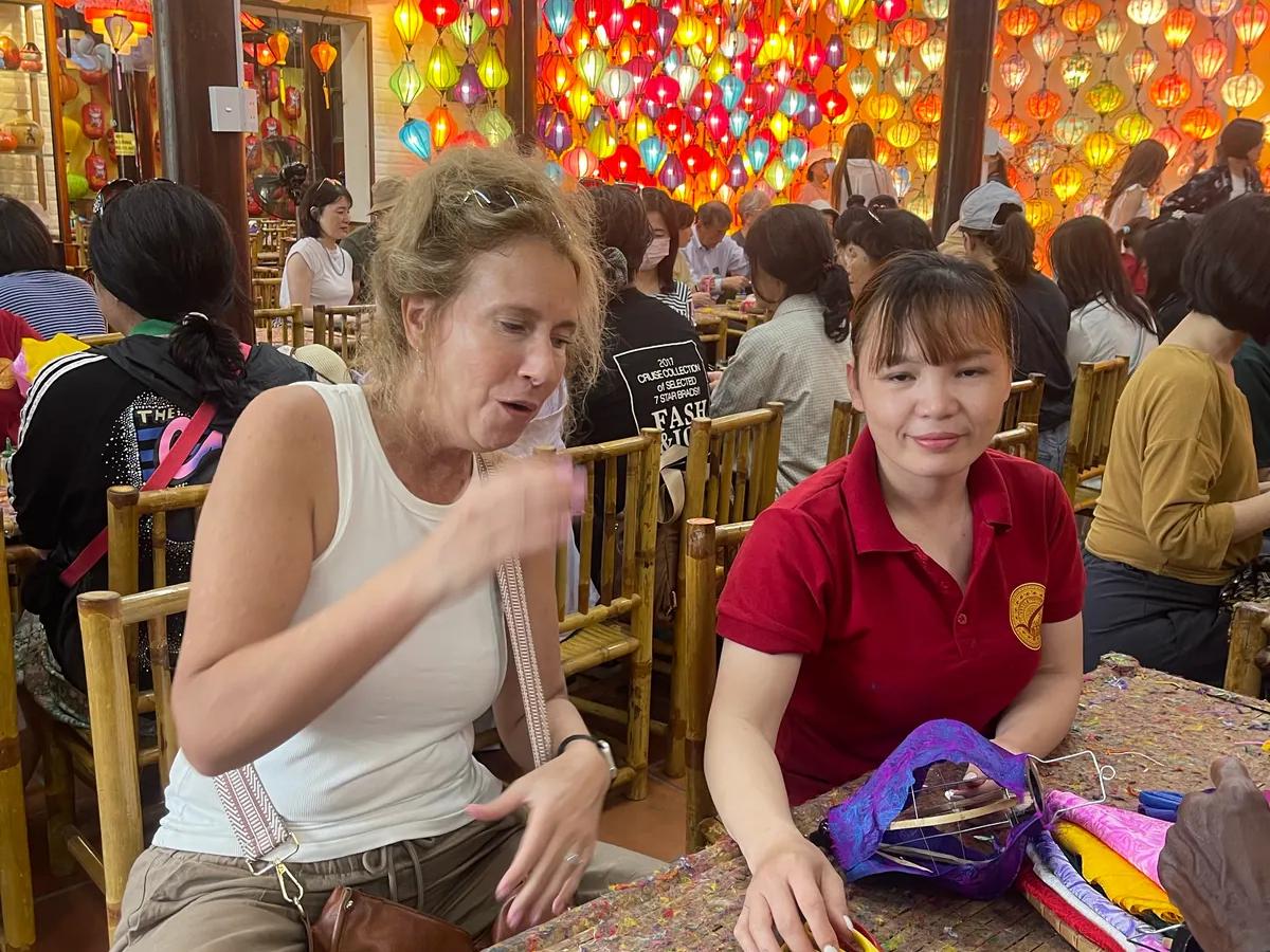 A guest making a silk lantern with a craftswoman in a Hoi An lantern workshop