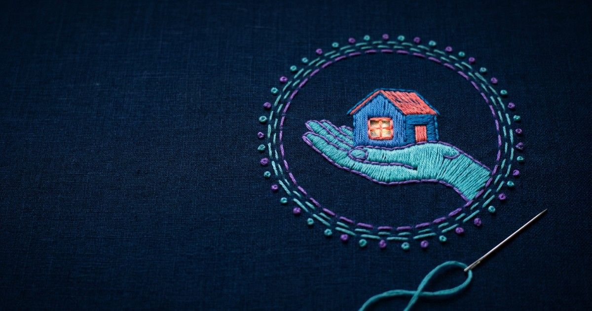 Embroidered open hand cradling a lit house within a stitched circle: consent governance and patient trust