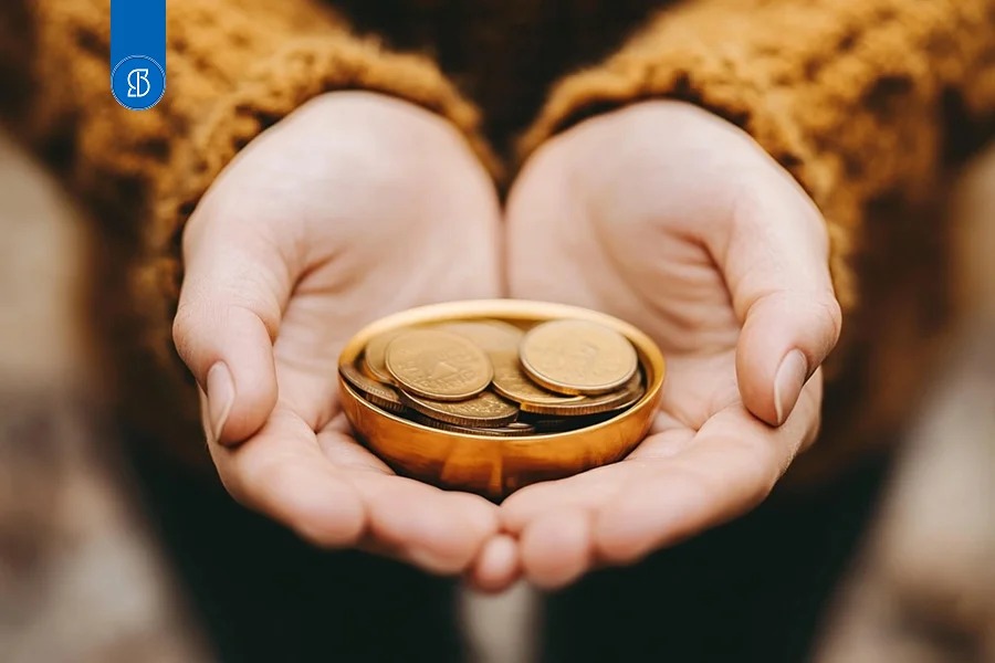 Mãos em concha segurando um pequeno pote com moedas douradas