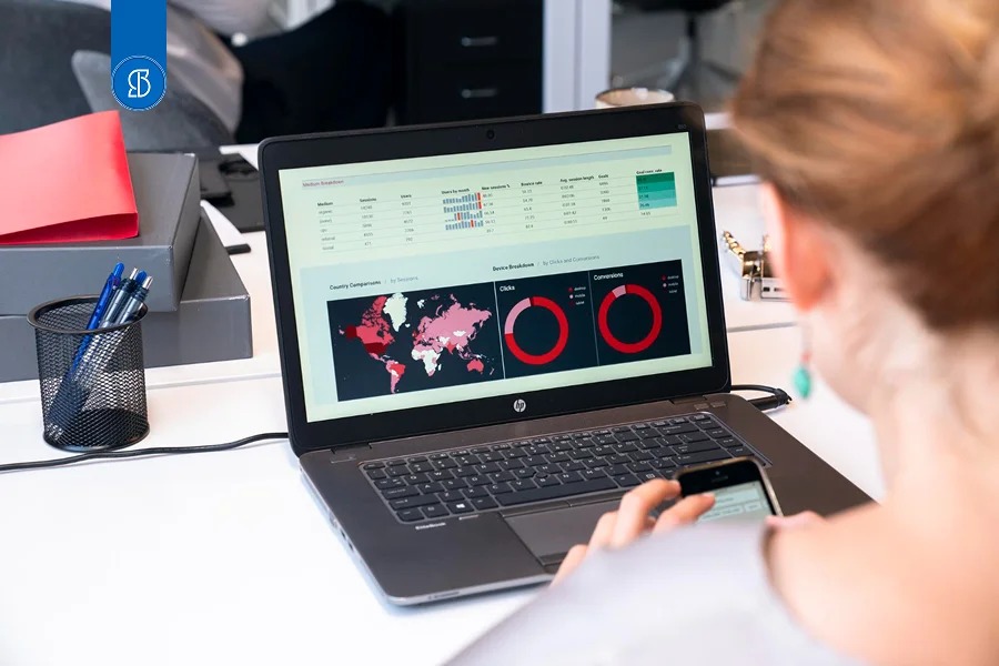 Mulher analisando um painel com mapa-múndi e gráficos circulares na tela do notebook