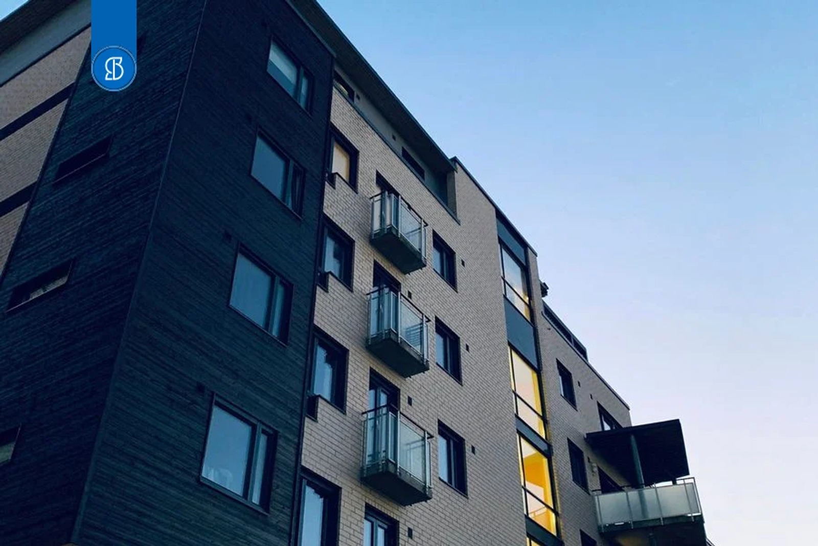 Fachada de um prédio de apartamentos com sacadas, vista de baixo, ao entardecer