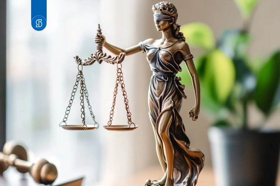 Estátua de bronze da Justiça com a balança, sobre mesa clara