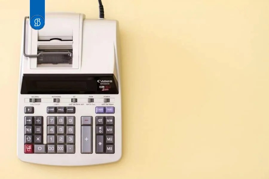 Calculadora de mesa com bobina de papel, sobre fundo amarelo claro
