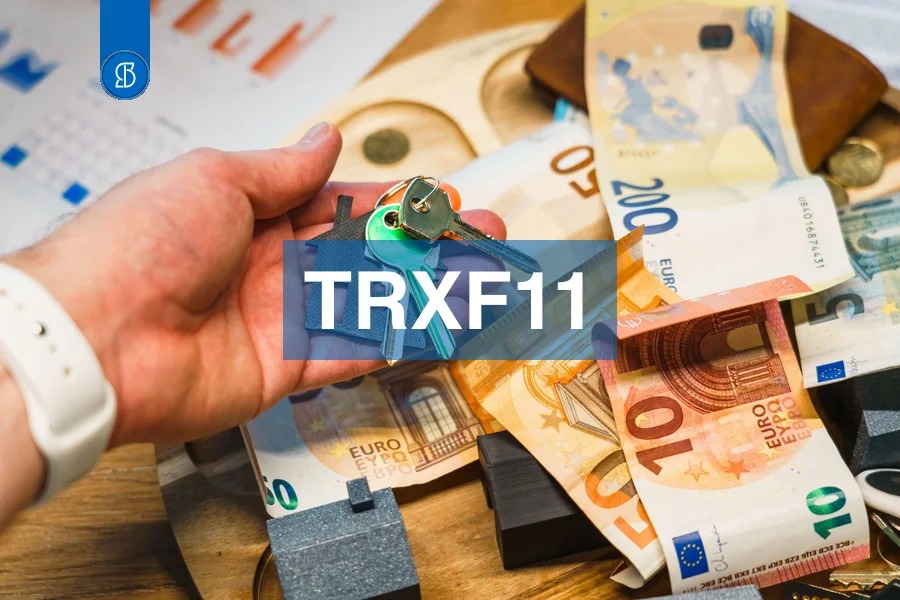 Mão segurando chaveiro em forma de casa sobre notas de euro, com o código TRXF11 em faixa azul ao centro