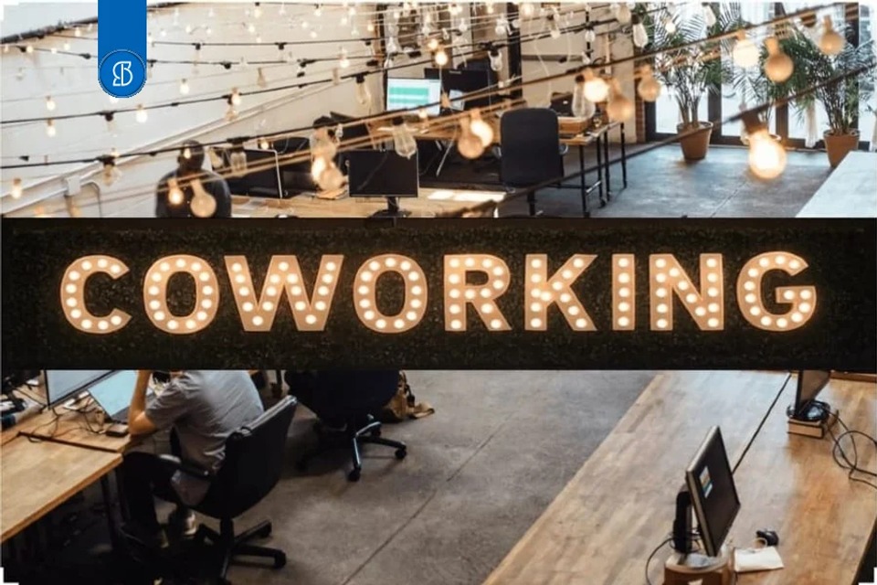 Espaço de coworking com pessoas trabalhando e um letreiro luminoso escrito COWORKING