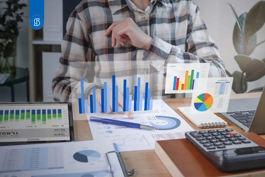 Pessoa de camisa xadrez analisando relatórios com gráficos projetados sobre a mesa