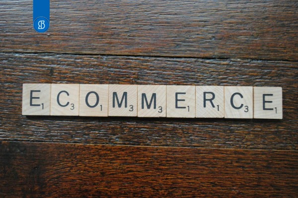 Peças de jogo de palavras formando a palavra ecommerce sobre uma mesa de madeira escura