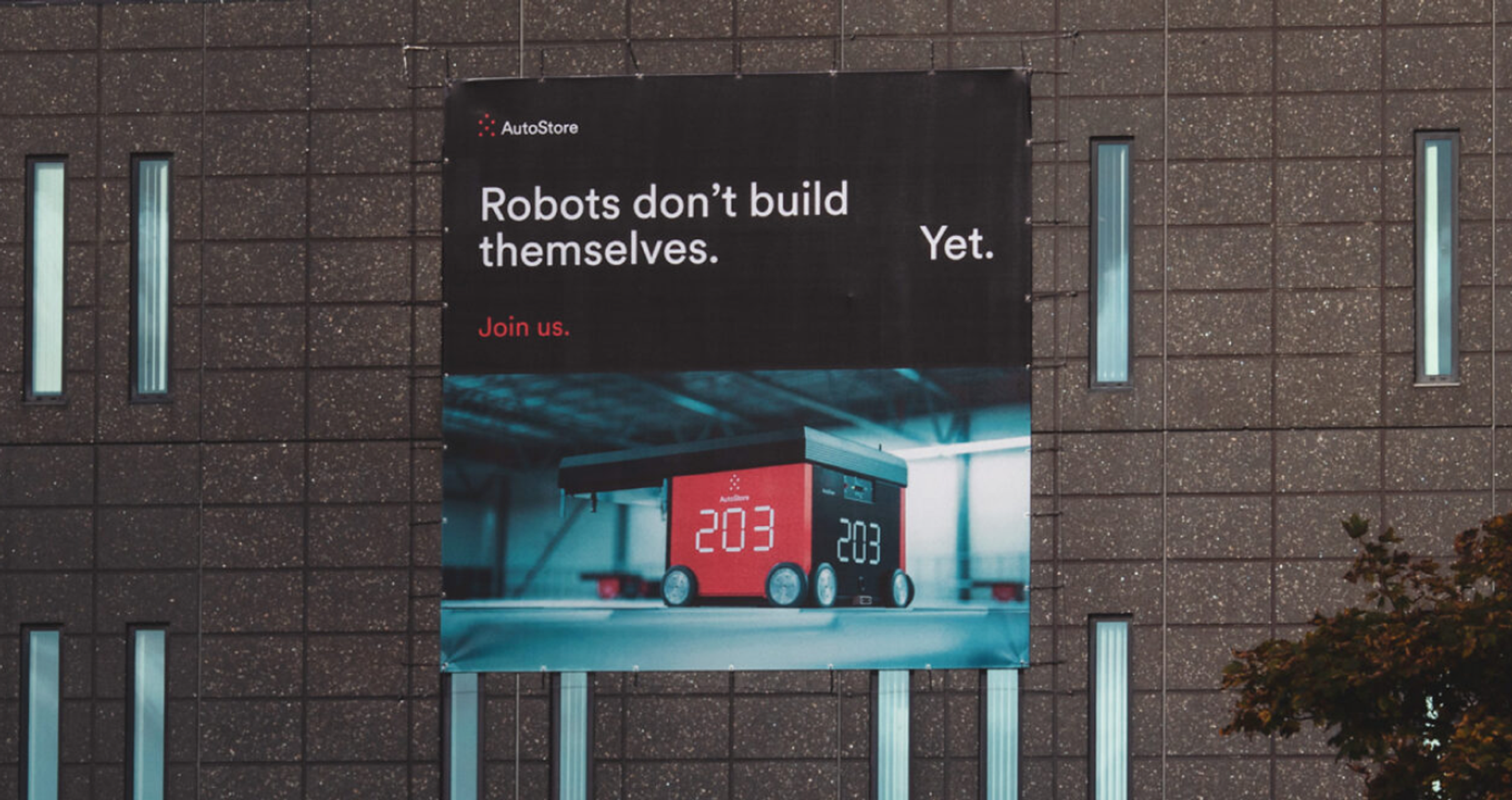 Fasadebanner på AutoStore-bygget: Robots don't build themselves.