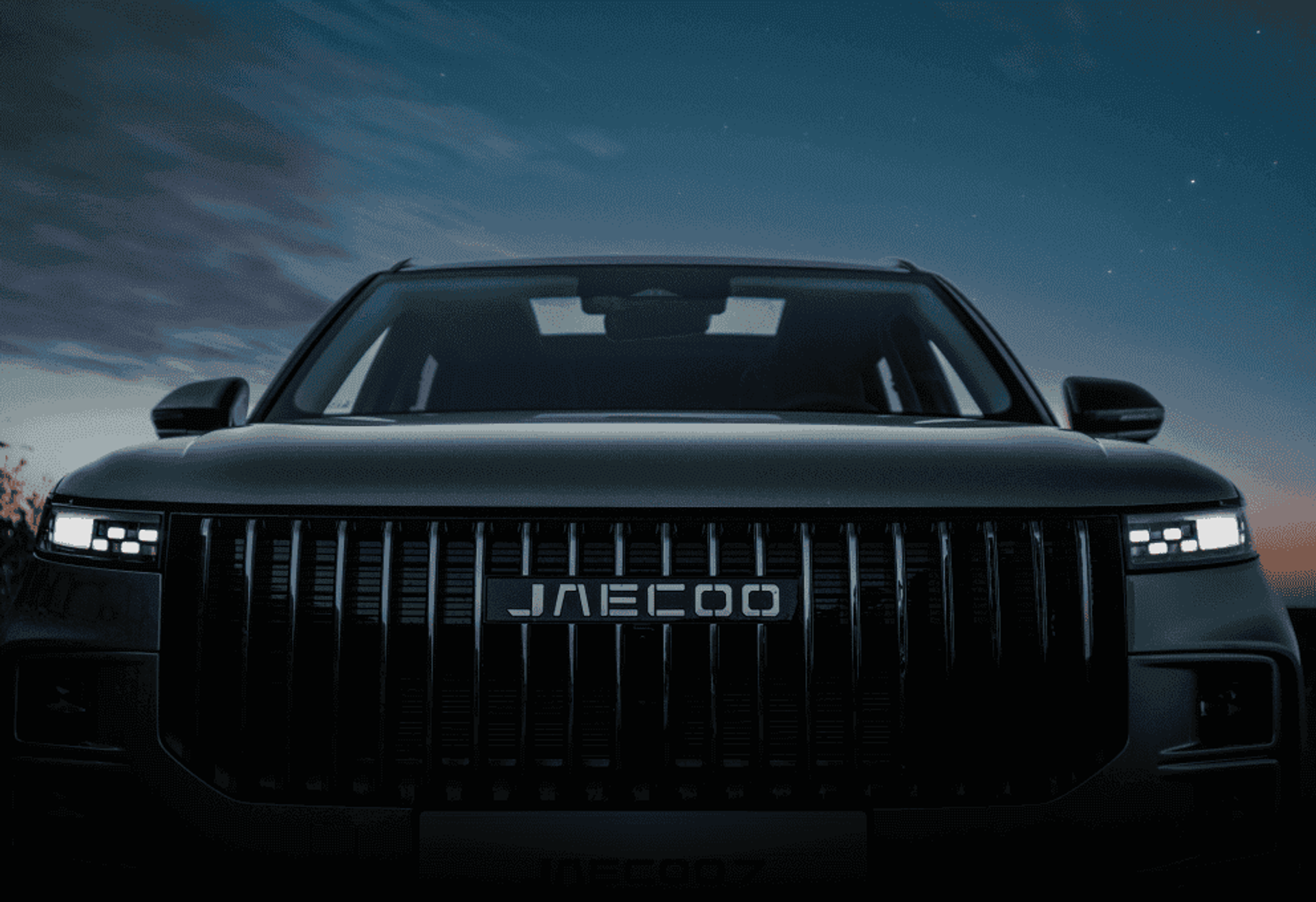 Front view of a JAECOO SUV grille at dusk under a starry sky