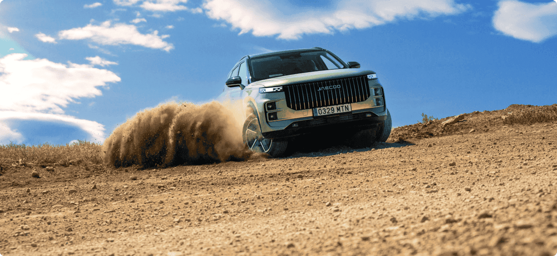 A JAECOO SUV kicking up dust while driving off-road under a blue sky