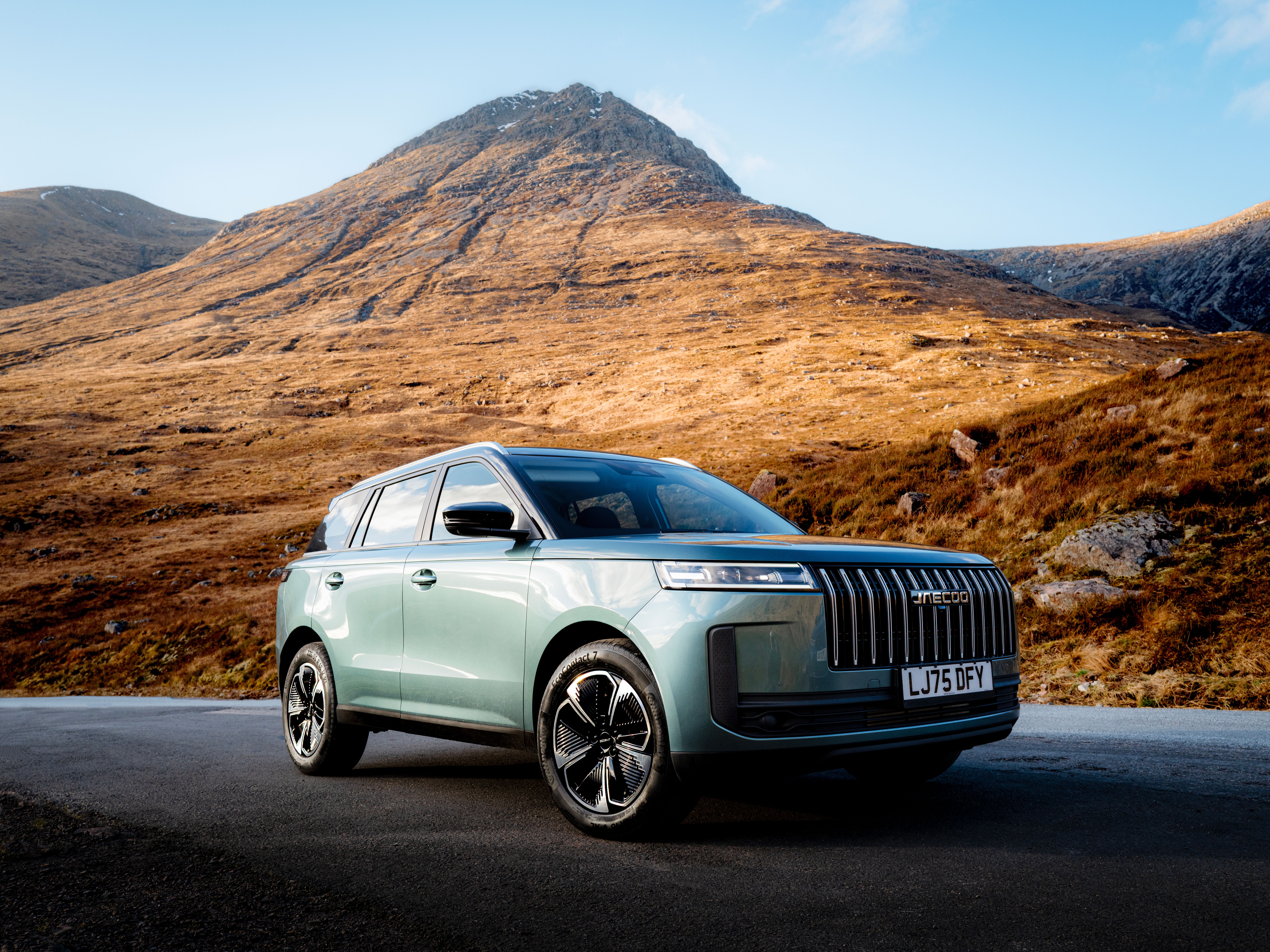 A green JAECOO 7 SUV parked in a desert landscape with mountains behind