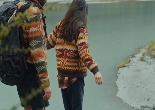 Two hikers standing beside a glacial lake