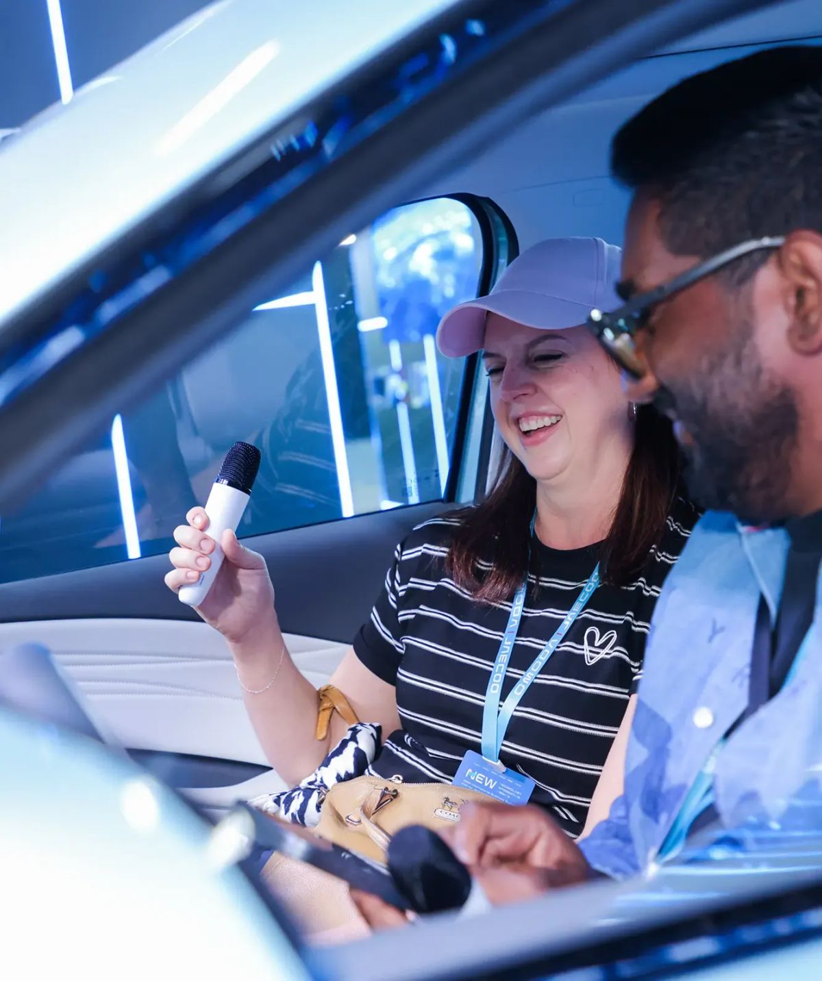 Two people using the JAECOO karaoke microphone inside the car