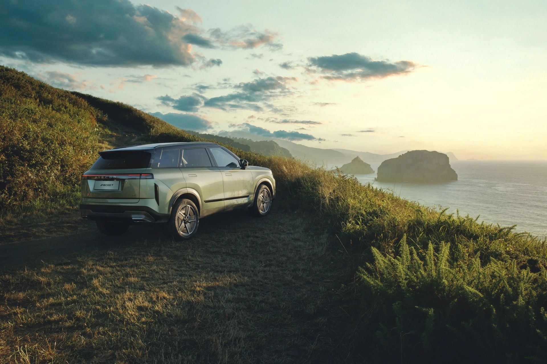 A JAECOO SUV parked on a coastal hillside at dusk