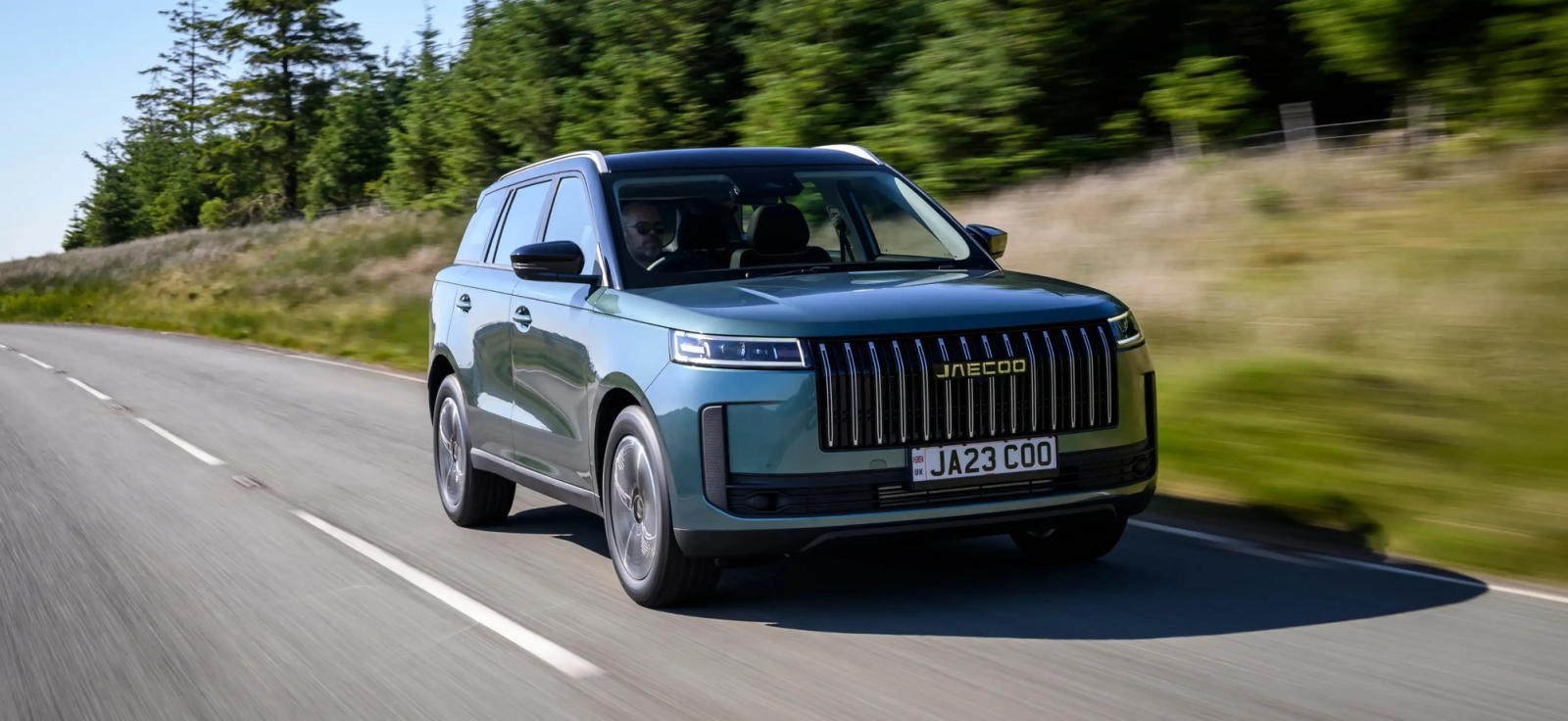 A teal JAECOO 7 driving along a tree-lined country road