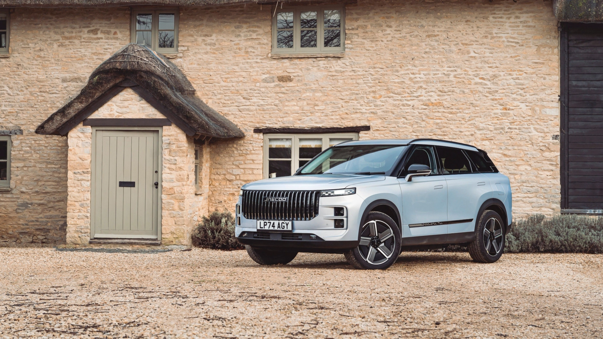 A JAECOO 7 SUV parked outside a stone cottage
