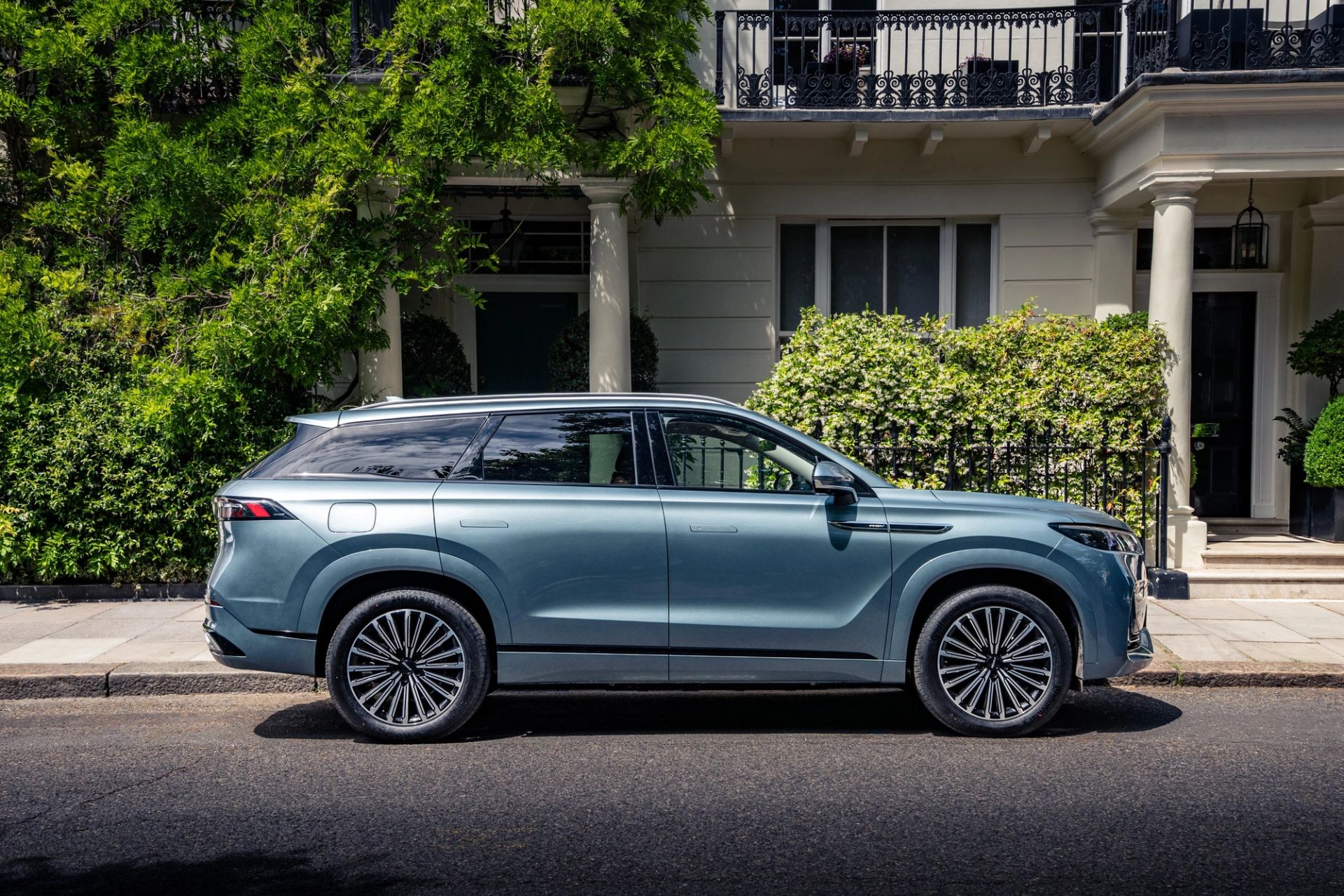 A blue JAECOO 8 SHS parked outside a white townhouse
