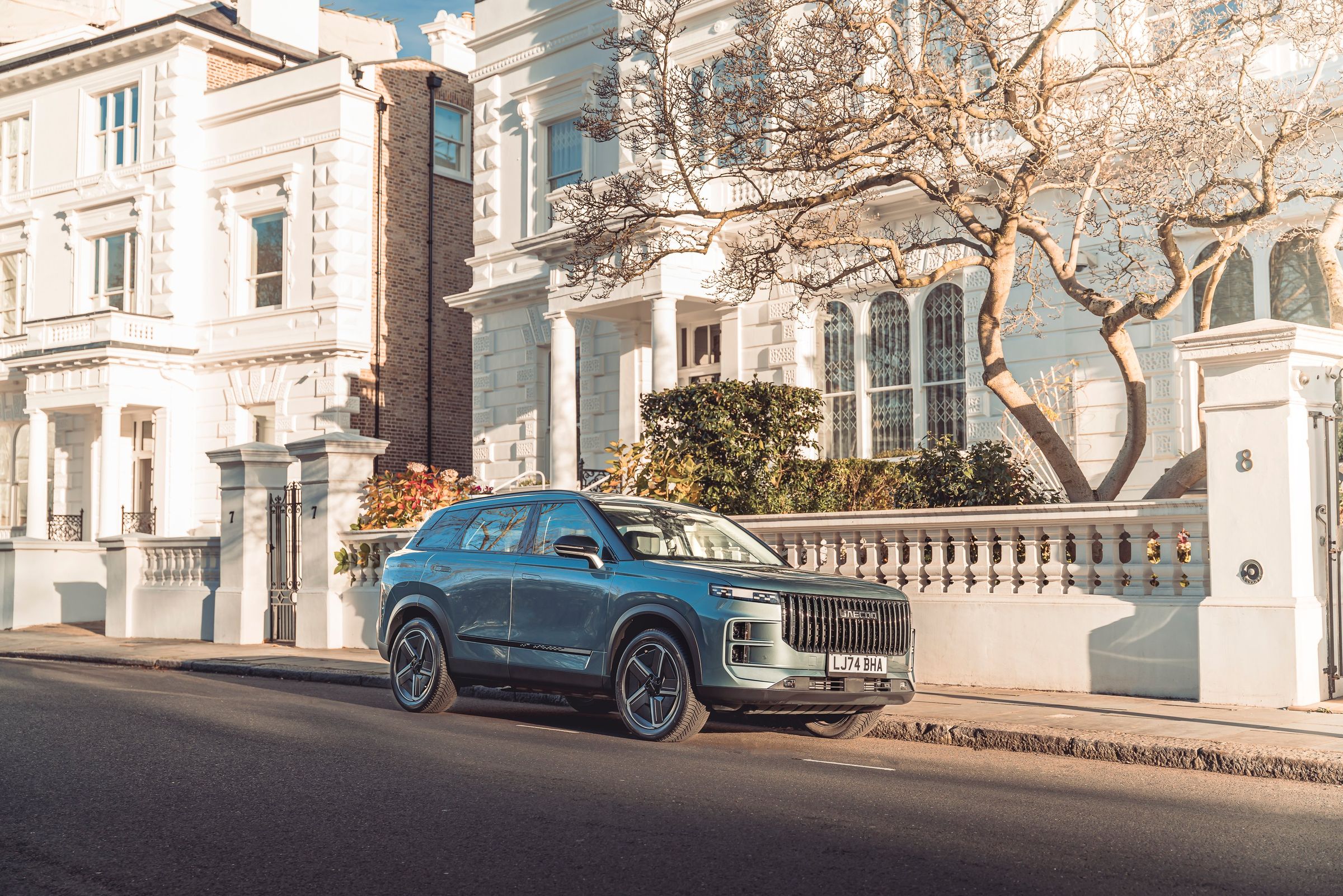 A JAECOO 7 parked on a street of white townhouses