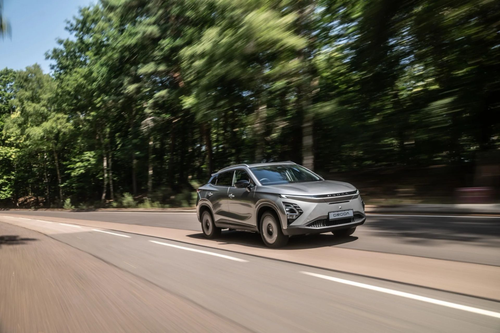 OMODA E5 driving on a tree-lined road
