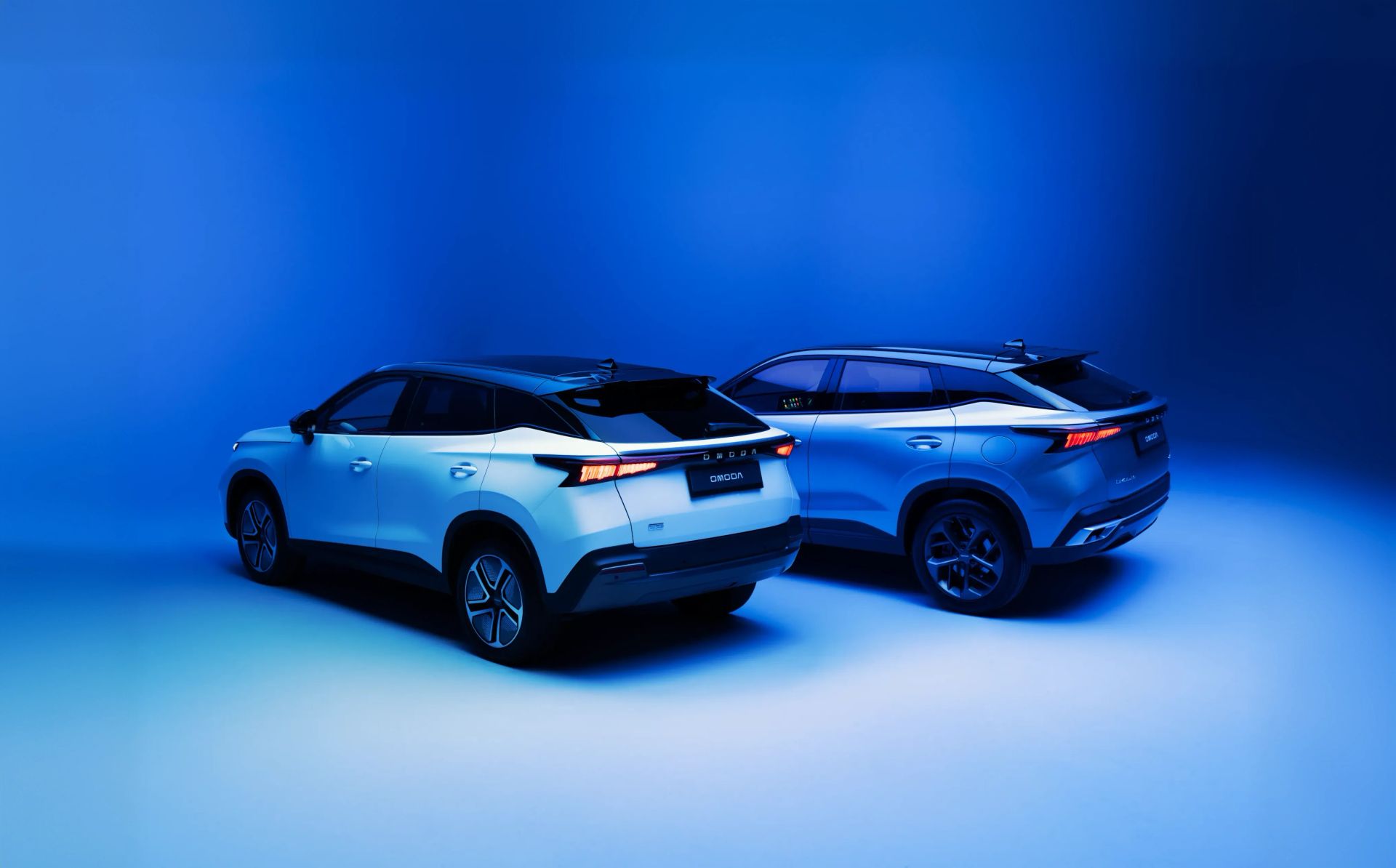 Two OMODA SUVs displayed against a blue studio backdrop