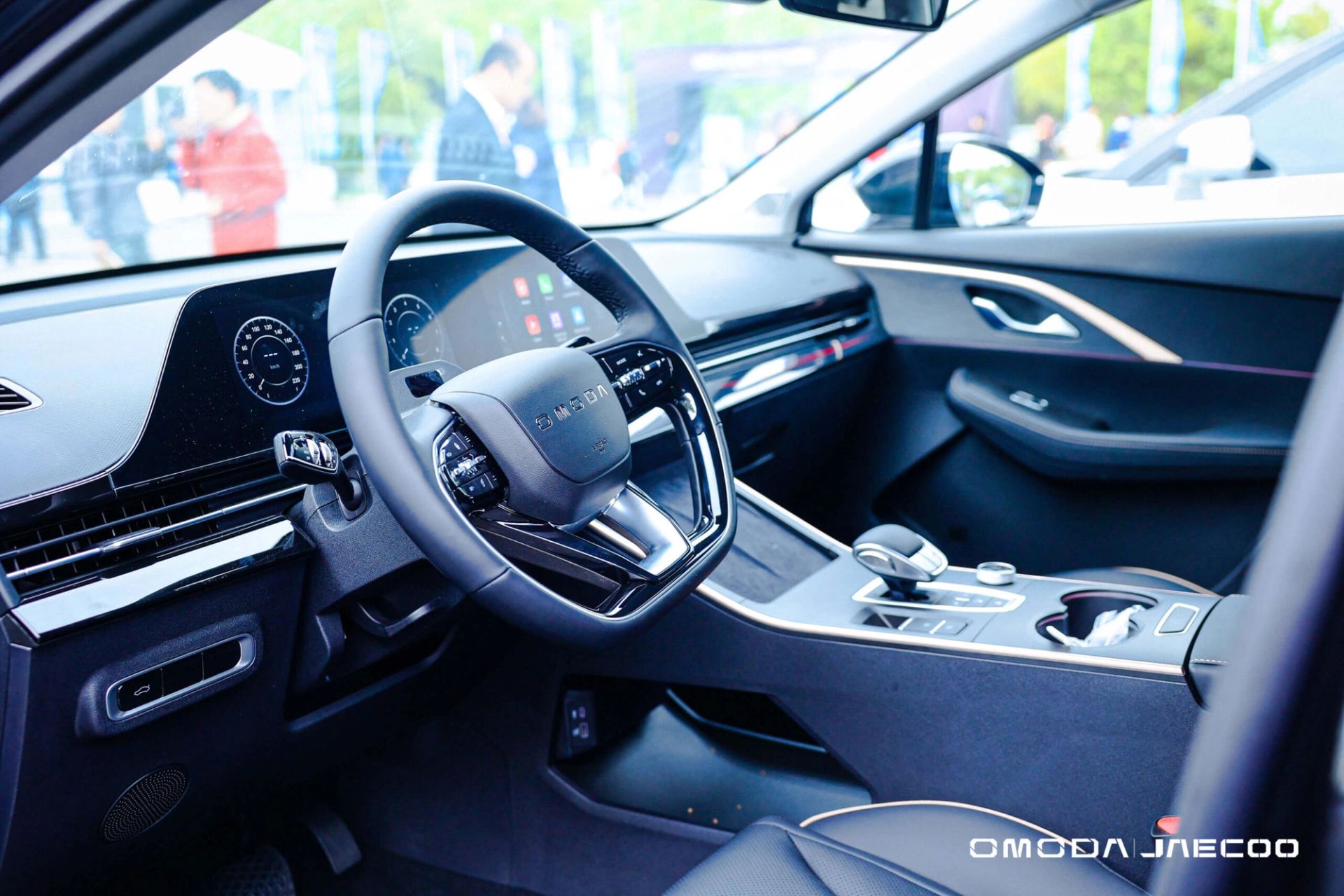View from inside a car dashboard towards people gathered at a test-drive event