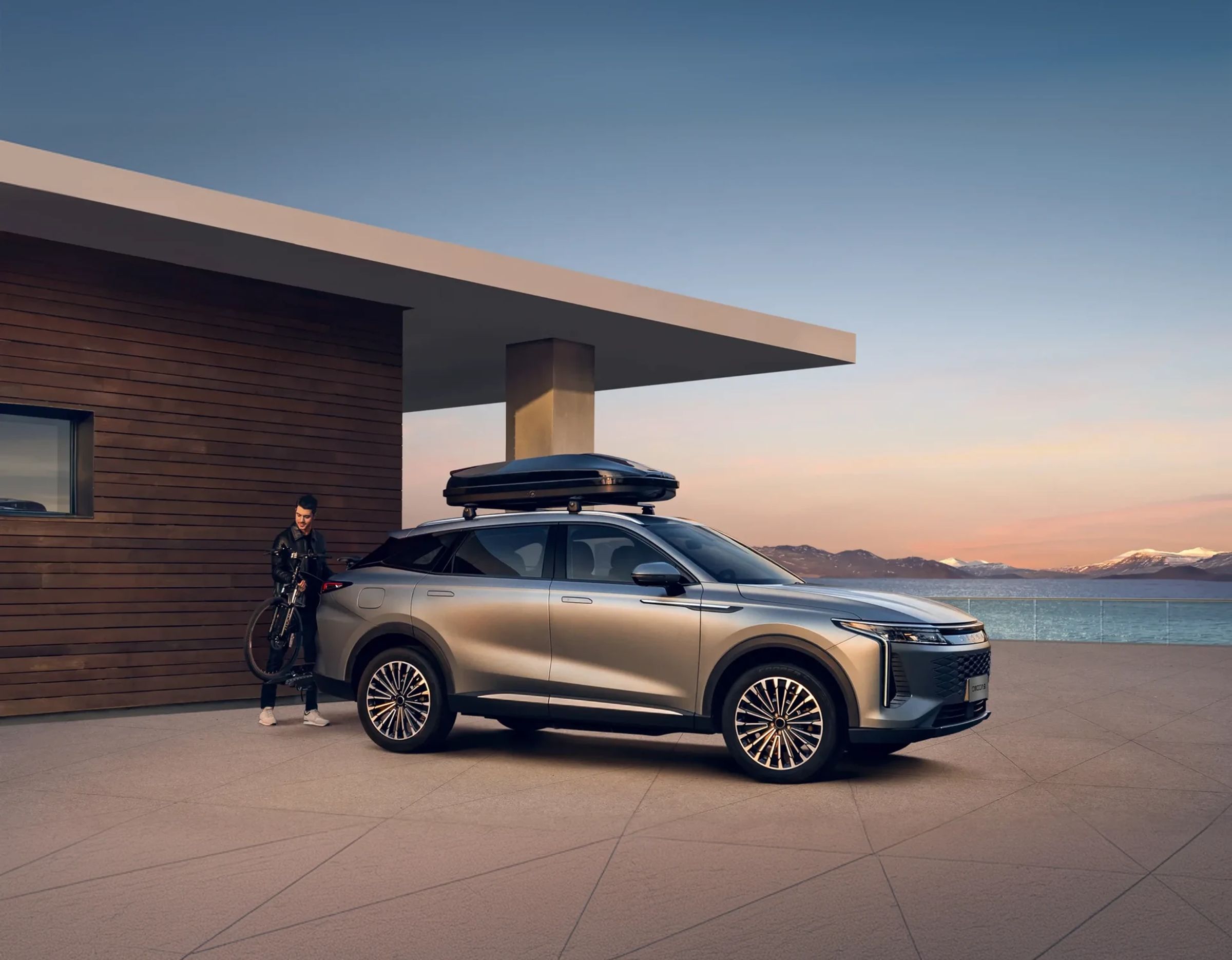 OMODA 9 parked by a lakeside lodge
