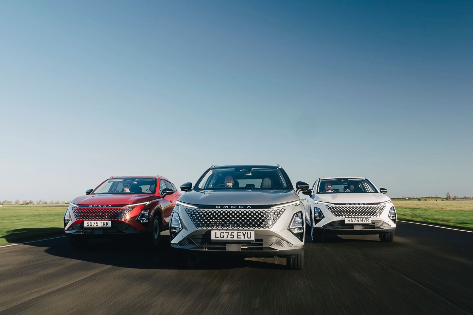 Three OMODA SUVs driving side by side along an open road