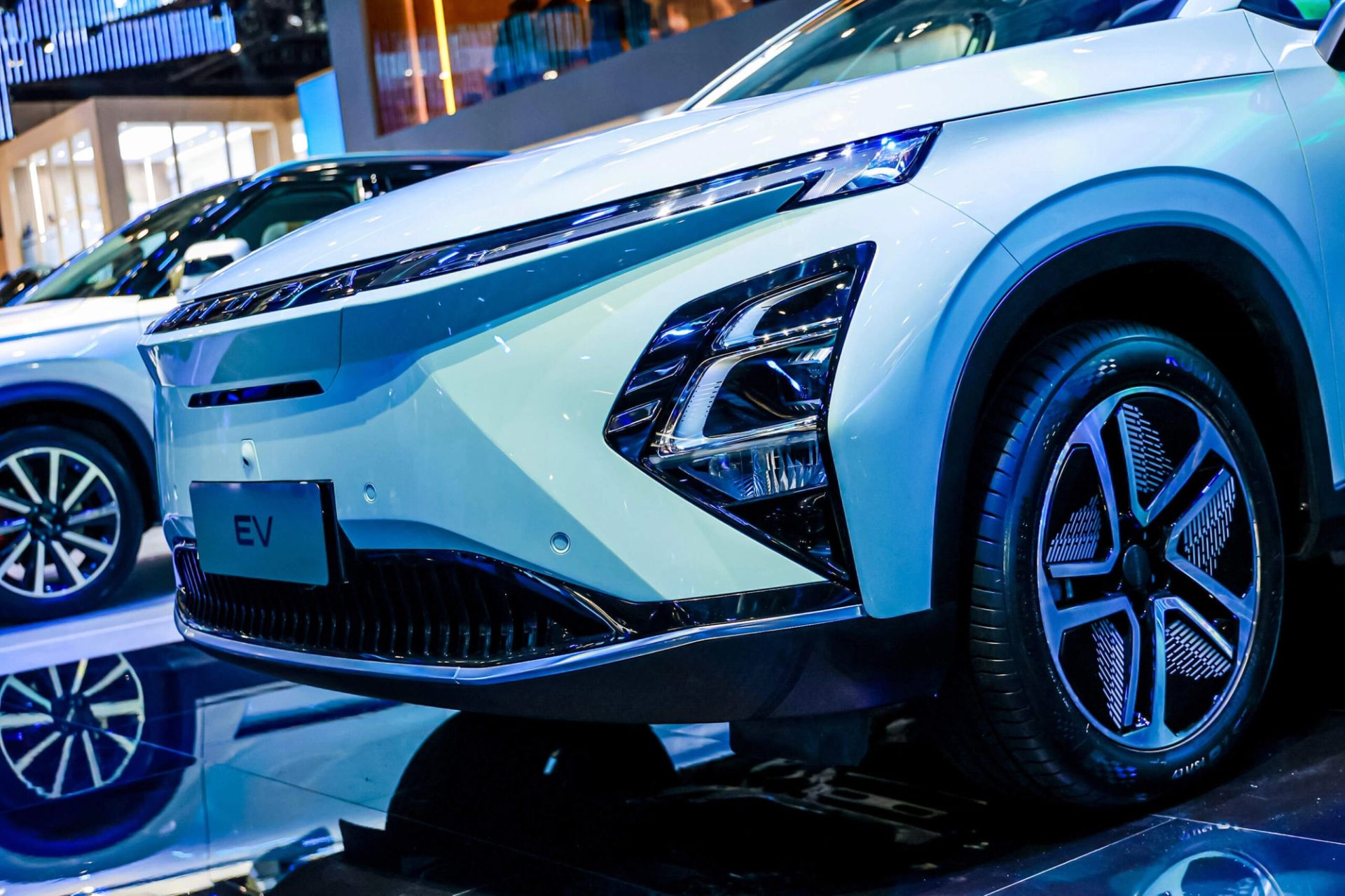 Close-up of a white SUV's headlight and grille at a motor show