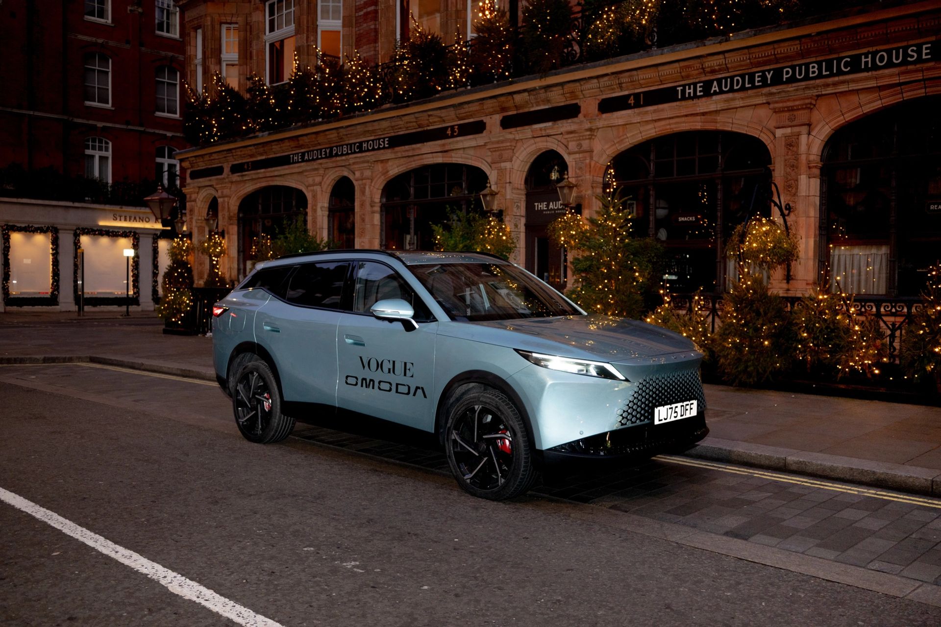 OMODA SUV parked outside The Audley public house, lit by festive lights