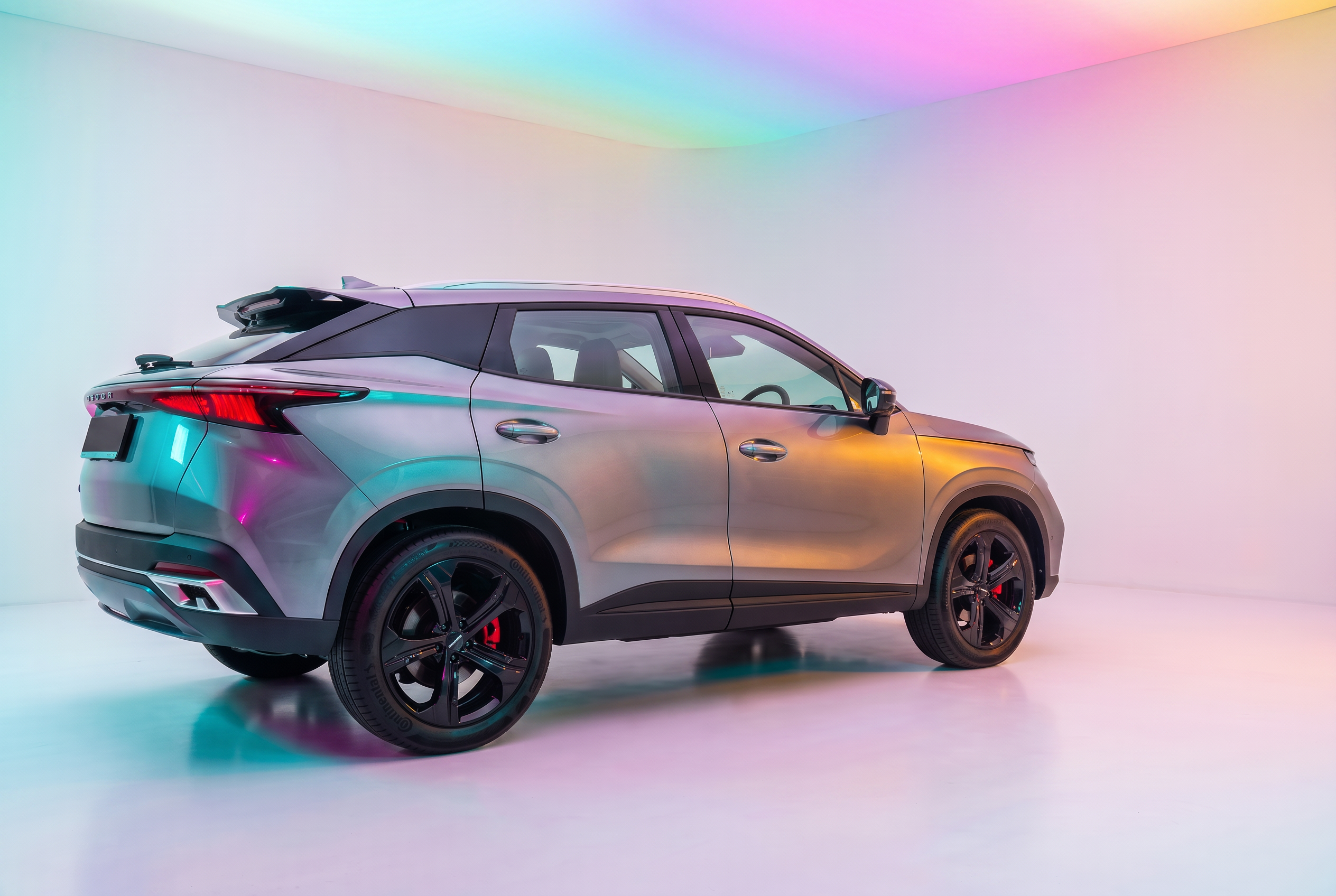 OMODA SUV rear three-quarter view lit by soft rainbow studio lighting