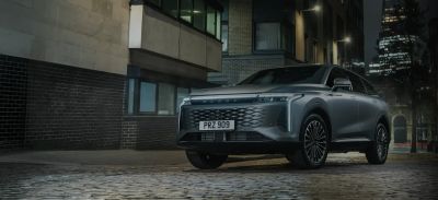 An OMODA SUV parked on a cobbled street in a city at night