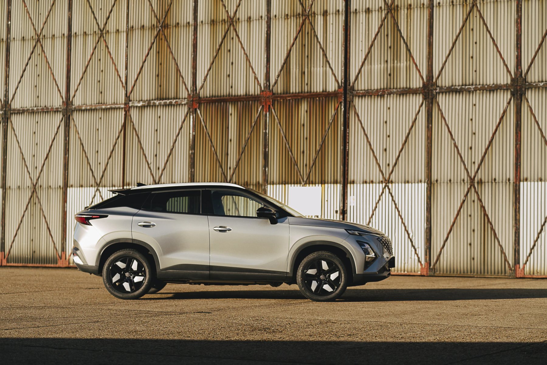 Silver SUV parked in front of a corrugated metal hangar at sunset
