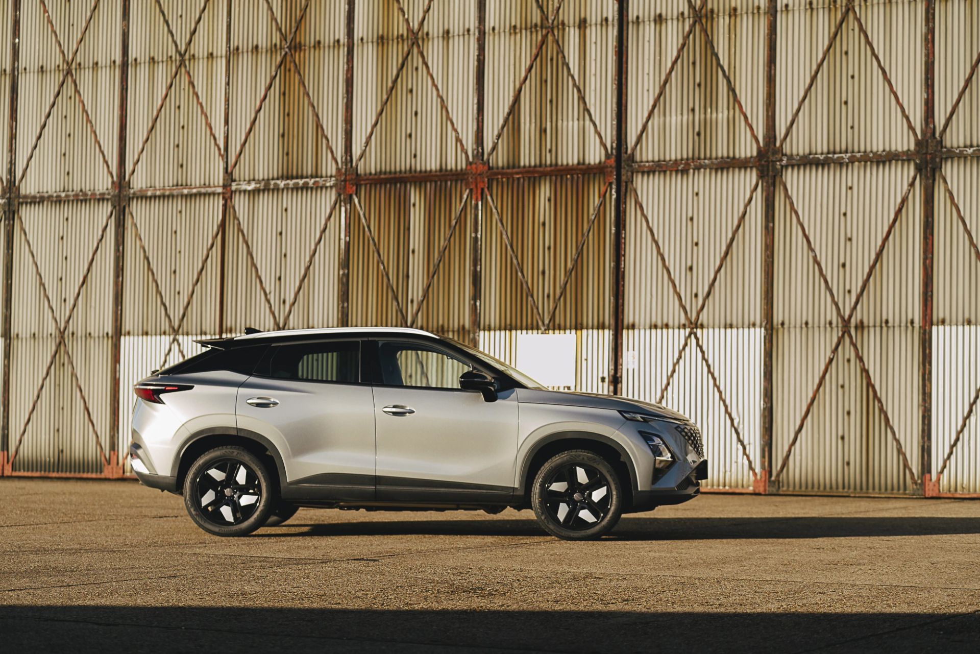 Silver SUV parked in front of a corrugated metal hangar at sunset