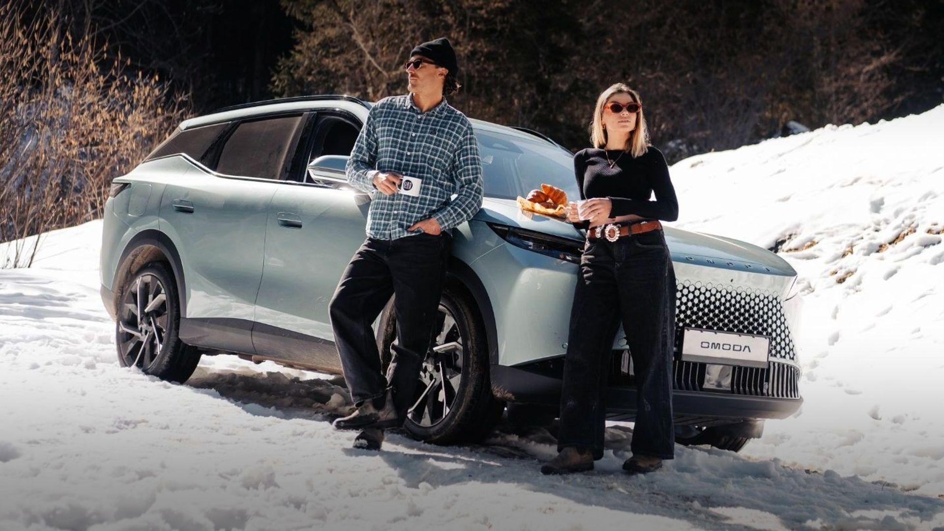 OMODA 5 parked in the snow with two people having coffee