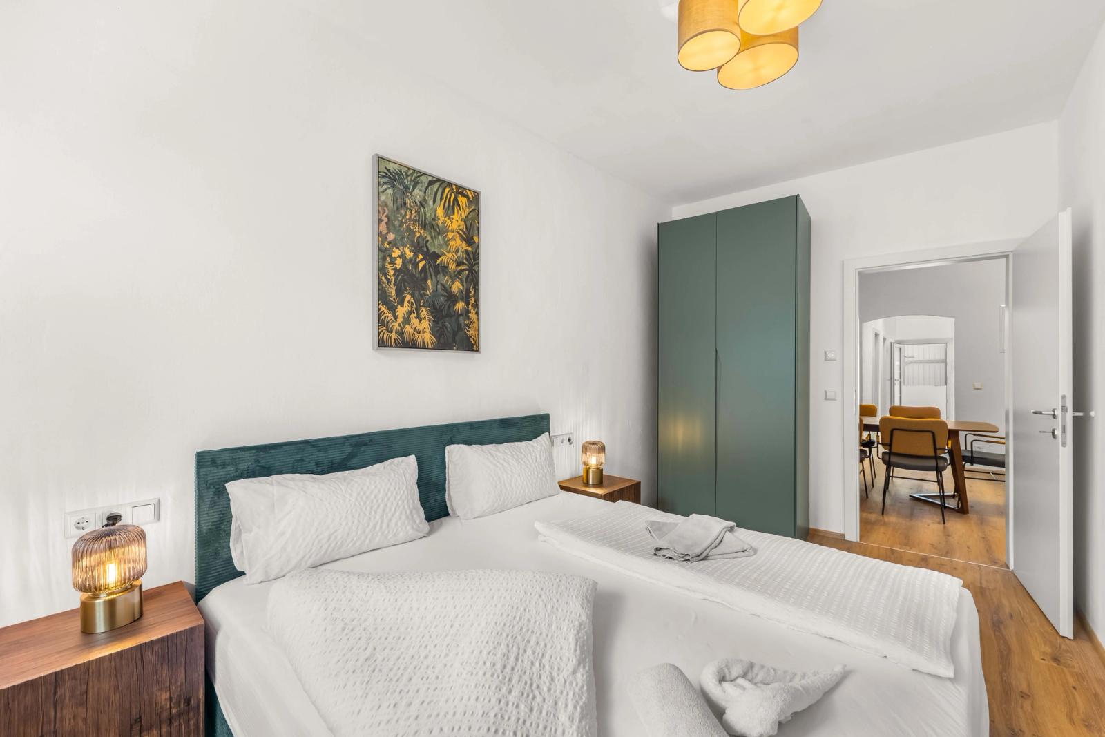 Dormitorio de un apartamento con servicios moderno gestionado por easy-flat en Villach, Austria, con una cómoda cama doble, mobiliario contemporáneo y un diseño luminoso y minimalista.