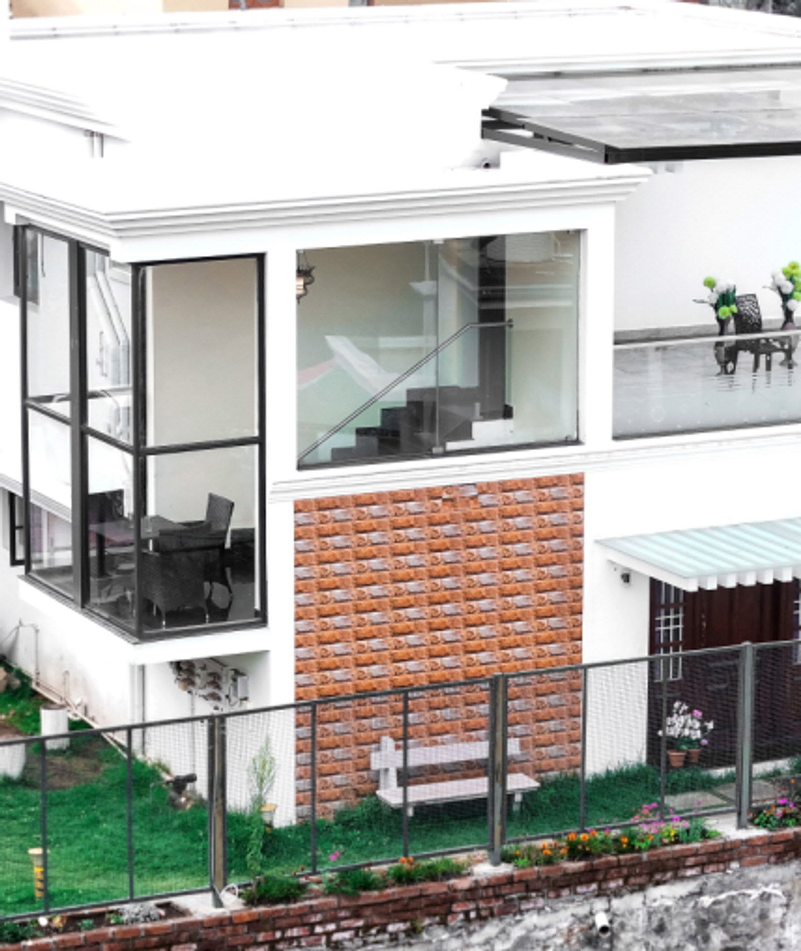 A modern white villa with glass balconies and a landscaped lawn overlooking the surrounding hills.